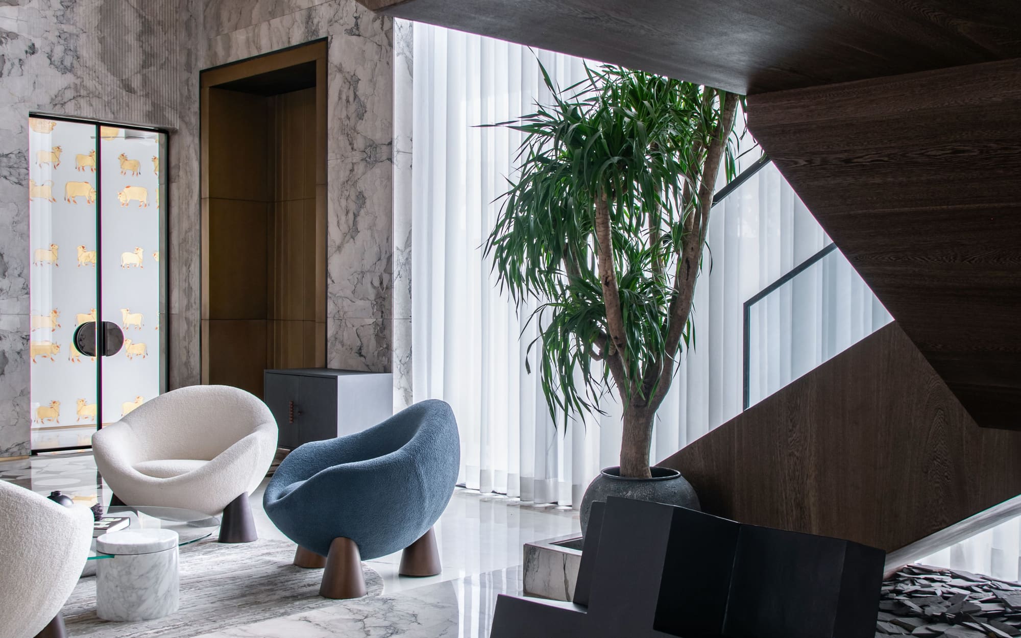 Double height living room with tall windows, a staircase, and sculptural seating