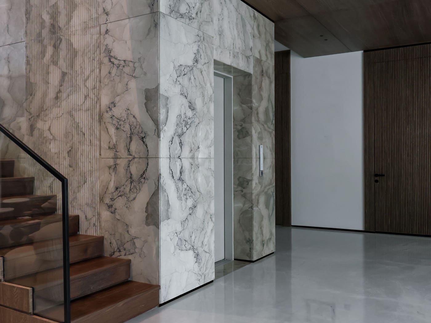 Marble clad entrance hall with a floating stair and dark timber